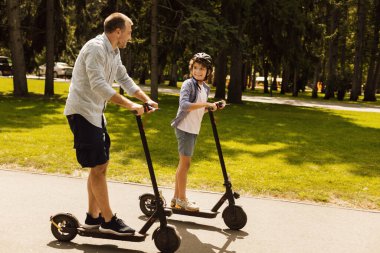 Mutlu adam ve babası e-scooter kullanıyor.