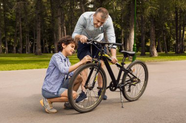 Neşeli baba ve oğulun bisiklet tamir ederken çekilmiş yakın plan portresi.
