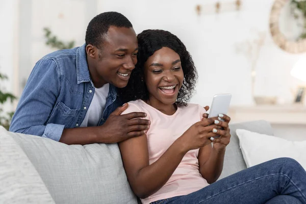 Joyful african couple playing game on smartphone