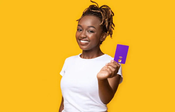 Menina africana feliz recomendando cartão de crédito, fundo amarelo — Fotografia de Stock