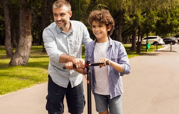 Boy learning to ride e-scooter with his dad — Stock Photo, Image