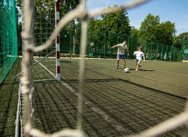 Sportive man playing football with little boy — Stock Photo, Image