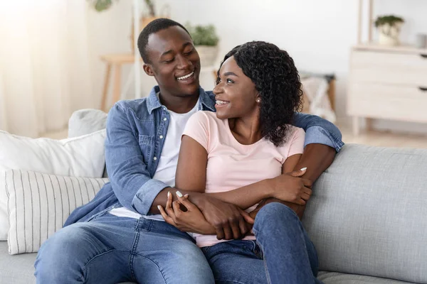 Feliz casal africano abraçando no sofá em casa — Fotografia de Stock