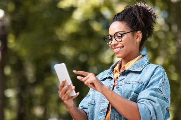 Bastante africana chica usando teléfono móvil navegar internet caminando fuera —  Fotos de Stock