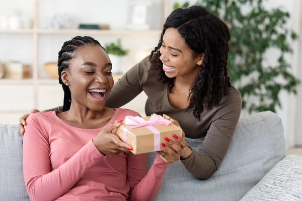 Black woman giving gift to her girlfriend at home