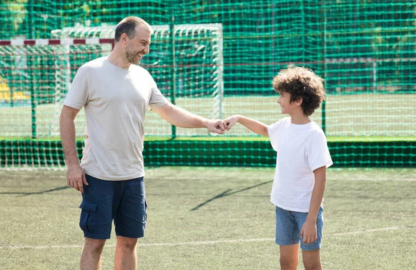 Man giving fist bump to boy ar football pitch — Stock Photo, Image