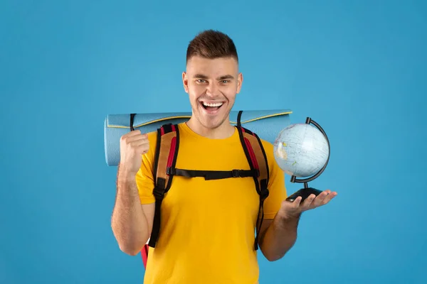 Joven viajero alegre con globo haciendo SÍ gesto sobre fondo azul — Foto de Stock