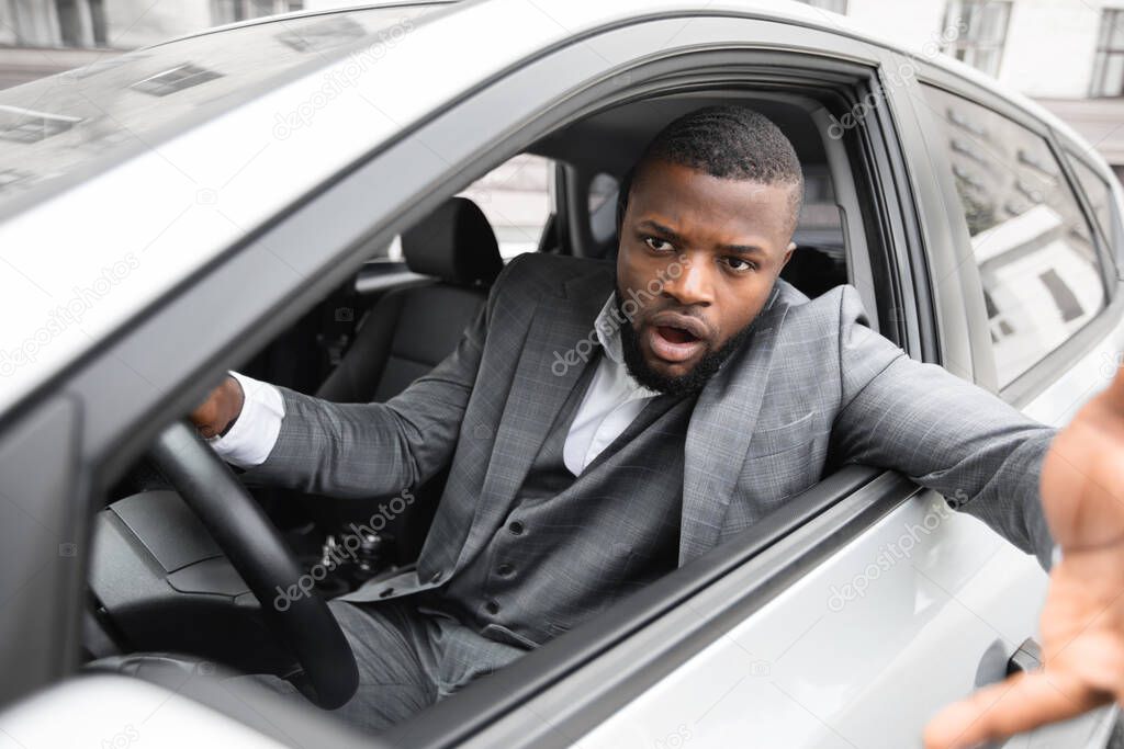 Angry black man driver gesturing and shouting while driving car