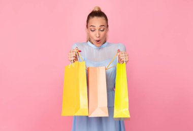 Alışveriş çantalarını tutan genç bayan içeri bakıyor.