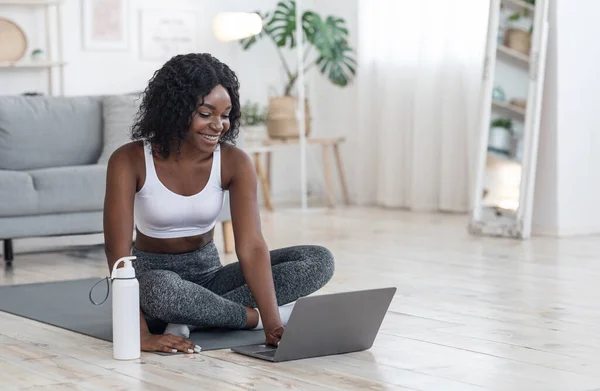 Fröhliche Afrikanerin übt zu Hause mit Laptop — Stockfoto