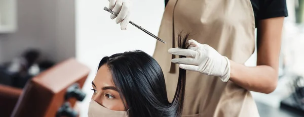 Close up de cabeleireiro corte pontas duplas para a mulher em máscara protetora, panorama — Fotografia de Stock