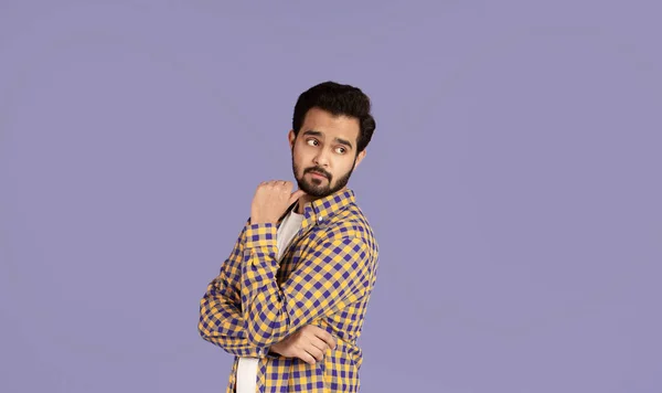Nachdenklicher indischer Typ blickt über seine Schulter in den leeren Raum, fliederfarbener Hintergrund — Stockfoto