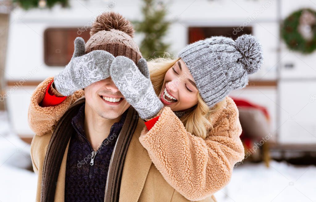 Outdoor Winter Portrait Of Cheerful Young Woman Covering Boyfriends Eyes With Hands
