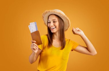 Elinde biletlerle pasaporta bakan duygusal bir kız.