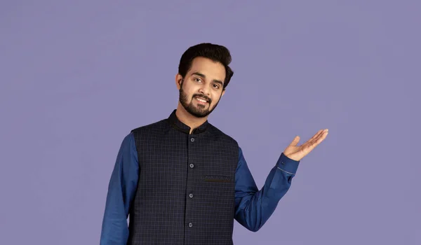 Fröhlicher indischer Mann präsentiert etwas auf violettem Hintergrund, Raum für Ihr Produktdesign — Stockfoto