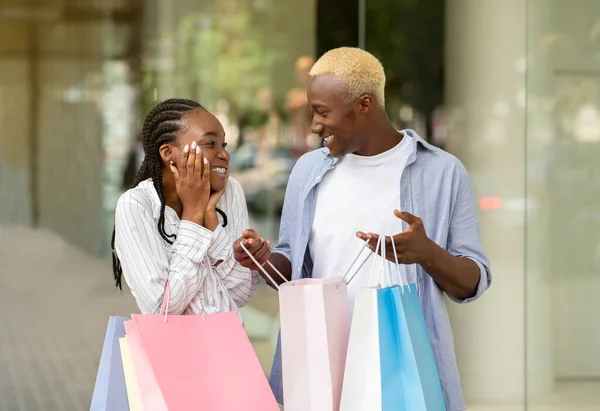 Cadeau voor winkelverslaafde. Vrolijke Afrikaan Amerikaanse man toont aankopen in zak, uiten geluk — Stockfoto