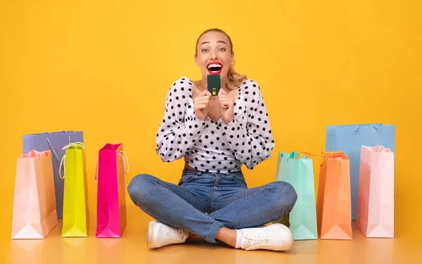 Aufgeregte Frau mit Plastikkarte denkt über Kauf nach — Stockfoto