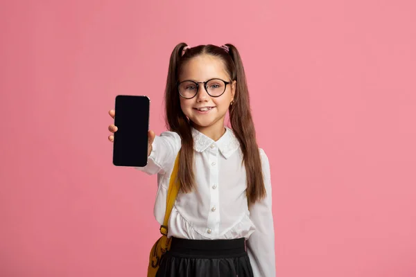 Technologie a škola. Malé dítě v brýlích v uniformě ukazující telefon — Stock fotografie