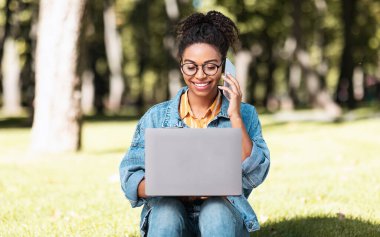 Bilgisayarlı kız telefonda sohbet ediyor. Dışarıda çalışıyor.