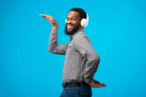 Усміхнений чорний чоловік насолоджується музикою з навушниками — стокове фото