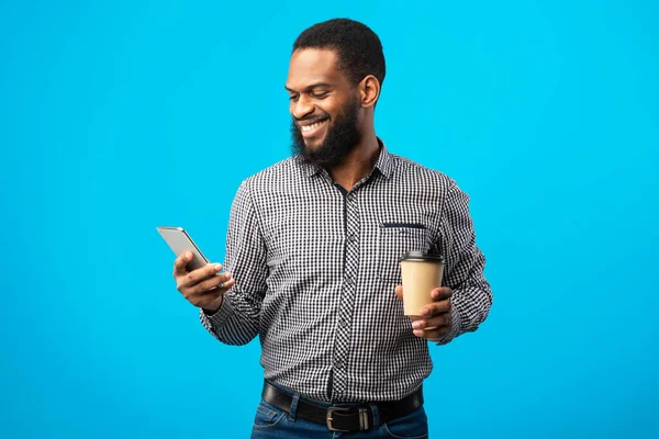 Tersenyum pria kulit hitam SMS di telepon minum kopi — Stok Foto