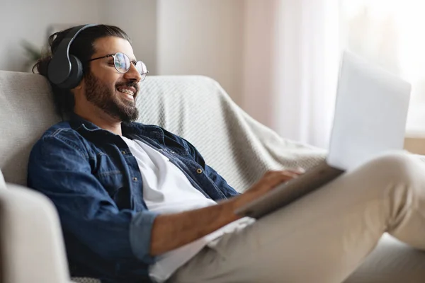 Indio freelancer hombre trabajando en el ordenador portátil en línea en casa y escuchar música — Foto de Stock