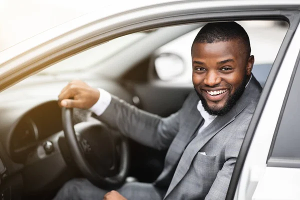 Веселий успішний чорний бізнесмен дивиться через вікно автомобіля — стокове фото