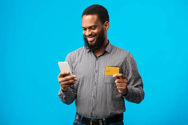 Zwarte man met creditcard en smartphone in de studio — Stockfoto