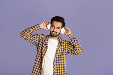 Gülümseyen Hintli adam kulaklıkla en sevdiği müziği dinliyor.