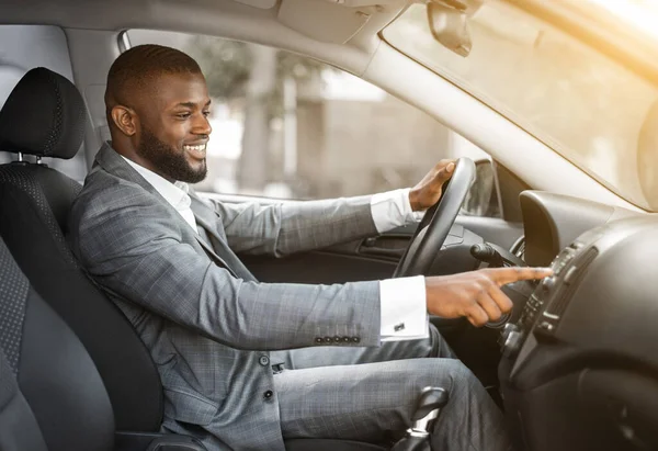 Afrikai férfi sofőr bekapcsolja a zenét az autóban, mielőtt mozog — Stock Fotó