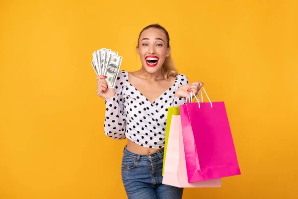 Femme excitée tenant de l'argent et des sacs à provisions — Photo