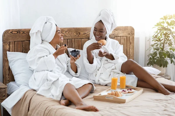 Mulheres negras alegres tomando café da manhã na cama — Fotografia de Stock
