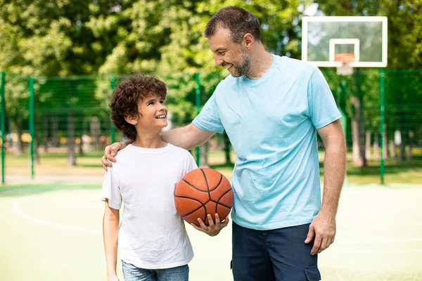 Hombre posando con hijo en campo de baloncesto vista frontal — Foto de Stock