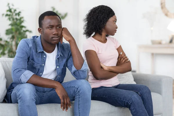 Upset black man and woman sitting on couch at home — Stock Photo, Image