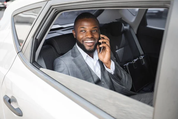 Arabada otururken telefonda konuşan neşeli siyah menajer.