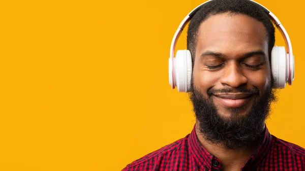 Sonriente hombre negro disfrutando de la música usando auriculares — Foto de Stock