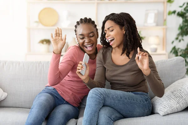 Dos alegres amigas jóvenes cantando en casa —  Fotos de Stock