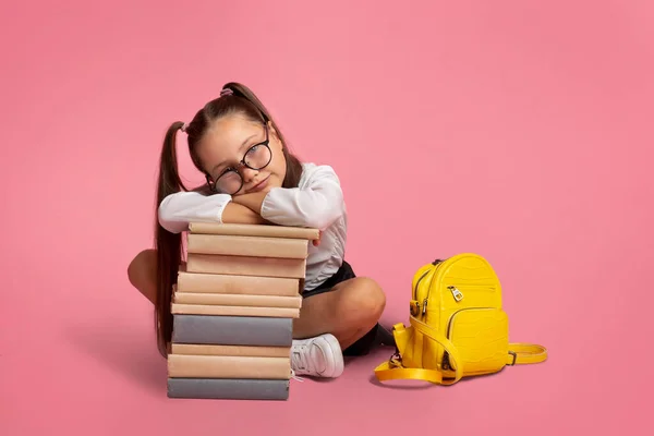 Conceito de outono e escola. Criança pequena em óculos com mochila senta-se perto da pilha de livros — Fotografia de Stock