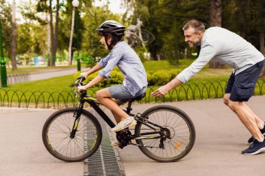 Oğlu mutlu babasıyla bisiklet sürmeyi öğreniyor.