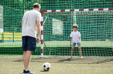 Küçük çocuk babasıyla futbol oynuyor.
