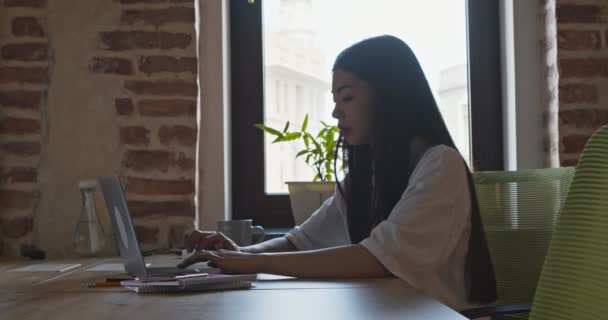 Menina asiática freelancer conversando com clientes on-line, digitando no laptop no café — Vídeo de Stock