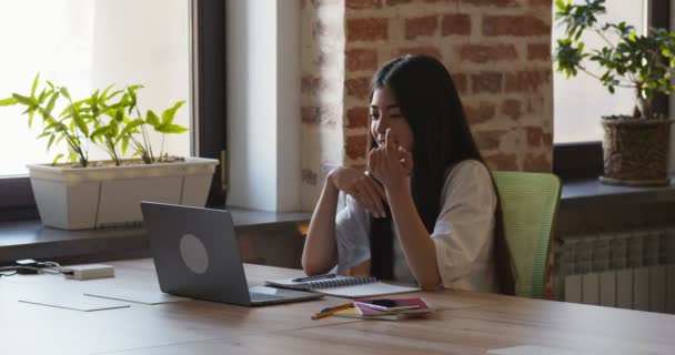 Mladá asijská dívka mluví s učitelem přes video chat na notebooku, sedí v kavárně — Stock video