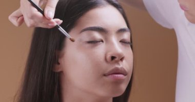 Milenyum Asyalı kız güzellik salonunda profesyonel makyaj yapıyor.