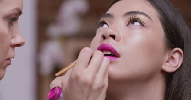 Hermosa chica asiática consiguiendo brillante maquillaje con lápiz labial rosa — Vídeo de stock