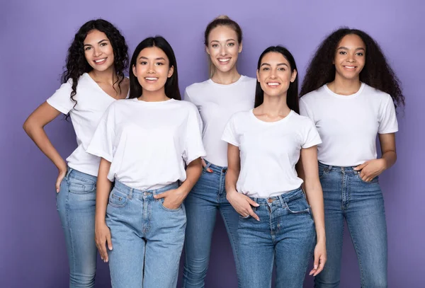 Gruppo di felici donne miste che si abbracciano in piedi su sfondo viola — Foto Stock