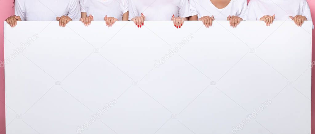 Unrecognizable Ladies Holding Blank White Poster Over Pink Studio Background
