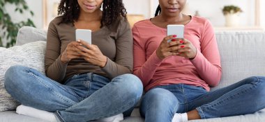 Evde cep telefonu kullanan tanınmayan siyahi kadınlar.