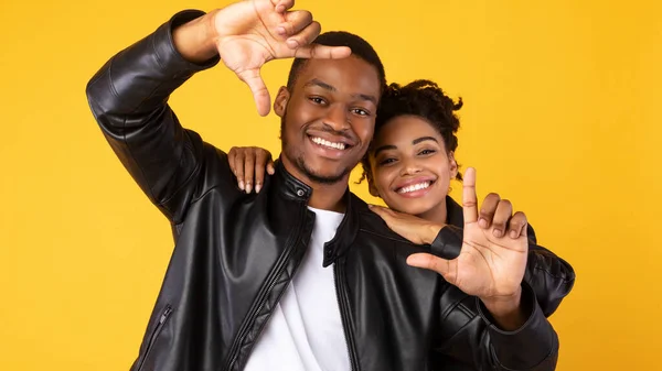 Alegre pareja afroamericana enmarcando sus rostros, fondo amarillo. Panorama — Foto de Stock