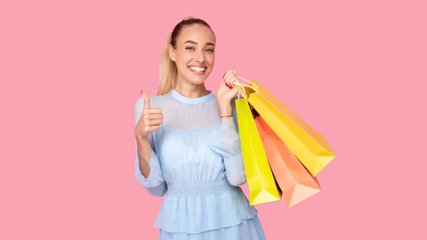 Menina segurando sacos de compras mostrando polegares para cima — Fotografia de Stock