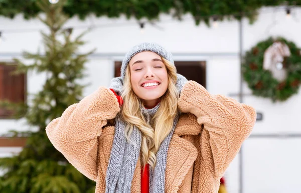 Sorridente ragazza bionda in cappello a maglia godendo mattina nevosa al campeggio invernale — Foto Stock